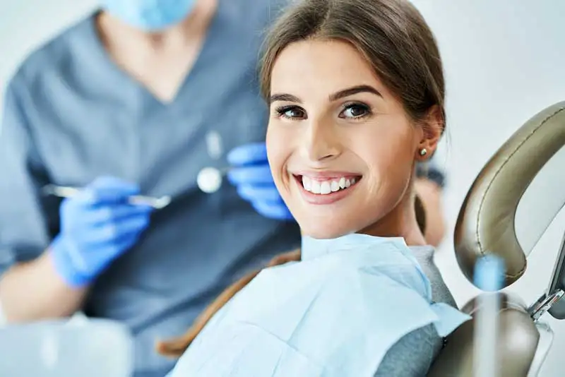 A woman sitting in a dentist chair smiling at McHenry Smile Center. 