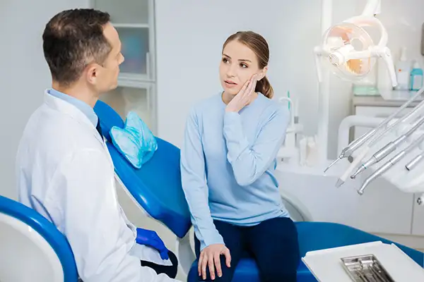 Concerned patient discussing her tooth pain with her dentist, while sitting in a dental chair, at McHenry Smile Center.