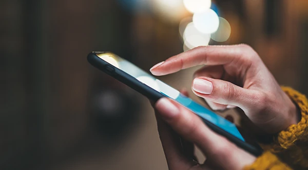 Close up of slender hands scrolling through a smart phone.