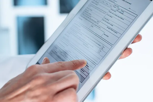 Close up of patient hands filling out patient forms on a tablet device, at McHenry Smile Center.